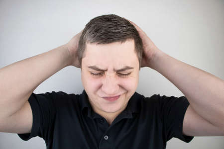 A man holds his head with his hands. Sensation of headache, migraine and dizziness. Headaches from...