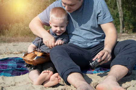 Dad and son launch a ship on the radio. Father shows the boy how to play with the boat on the remote control. The concept of relaxing on the beach and a happy childhoodの写真素材