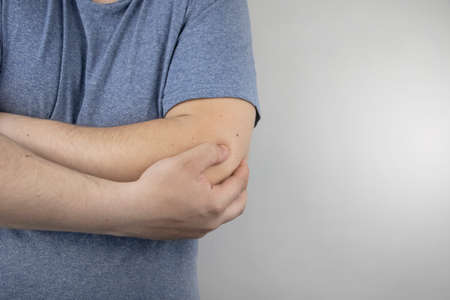 A man suffers from elbow pain. Damaged elbow joint, bone fracture, or sprain. Hand injury and flexion pain conceptの写真素材