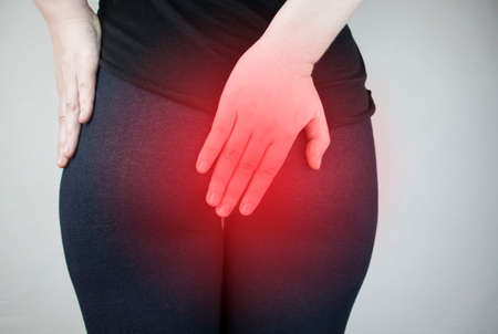 A woman holds his hands to the ass feeling pain. Conversion of pain in the rectum, hemorrhoids and pain in the excretory system of the body. Frequent bowel movements.の写真素材