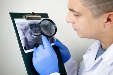 A dentist doctor examines a radiography of the teeth of a patient who has problems and teeth are inserted. The concept of research and diagnosisの写真素材