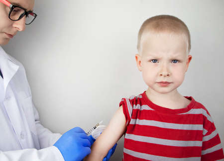 A doctor injects a vaccine into the boyâs shoulder. The concept of vaccination of children and the prevention of infectious diseases.の写真素材