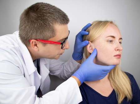 A doctor trichologist conducts a study of the hair of a blonde. Alopecia treatment. Hair loss,...