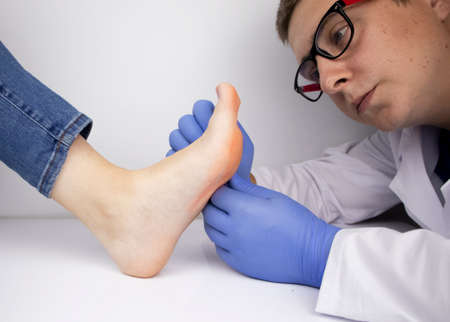 A dermatologist examines a toenail affected by a fungus. Treatment of mycosis and assistance to patients with fungal diseases.の写真素材