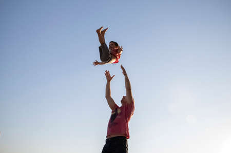 A caring father tosses his son in the air and catches him.の写真素材