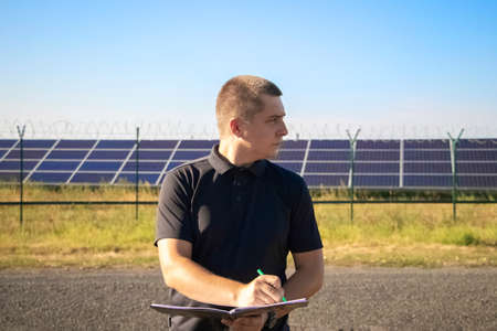 An angry man looks at the idle car engine. The driver tries to explain the cause of the breakdown to the mechanic using his smartphone and call for help. Concept of unpleasant situations on the roadの写真素材