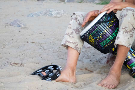 A man plays an African djembe drum against a blue sky. Creativity, rest and relaxation. Ethnic...