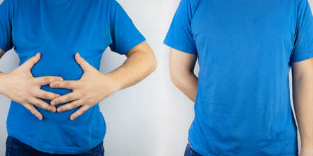 Conceptual photography. The man holds a red ball near his belly, which symbolizes bloating and flatulence. Then he brings a needle to it to burst the balloon and thus get rid of the problem.の写真素材