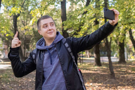 A man in a leather jacket looks at the phone in the middle of the forest. Social media immersion,...