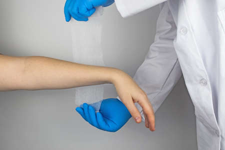 The traumatologist puts a bandage on the forearm of the female patient. The concept of help with...