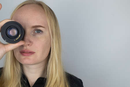 A woman tries on a camera lens instead of an eye. The concept of the photographer's work and the...