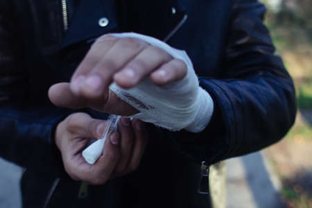 The fighter is bandaging his hands. The concept of preparation for a fight, sports competition, boxing and kickboxing. A man in a leather jacket.の写真素材
