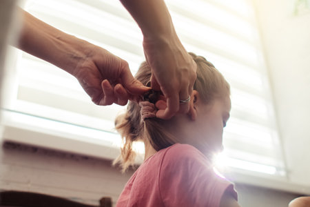 Mom is combing her daughter's hair. Taking care of baby's hair. The concept of a happy childhood and a good attitude towards children. Happy familyの写真素材