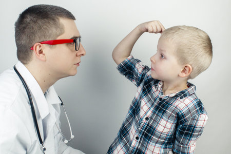 A boy complains to a traumatologist about a headache. Treatment of skull injuries and head bruises. Pain from symptoms of flu, colds, covid 19, rotavirus. The pediatrician examines the boyの写真素材