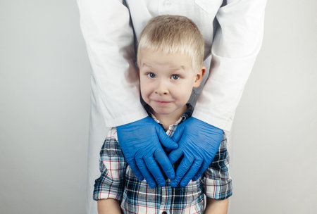 The child hugs the doctor. Examination of the boy by a pediatrician. Child protection, healthcare and medical care concept. Close-up on white backgroundの写真素材