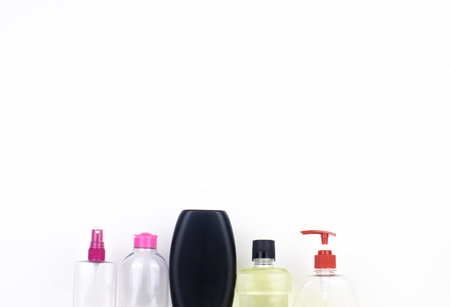 Isolated bottles of detergents on a white background. The hand takes the jars of detergents. In the photo, shampoo, micellar water, liquid soap and mouthwash. Household chemicals in colored containersの写真素材
