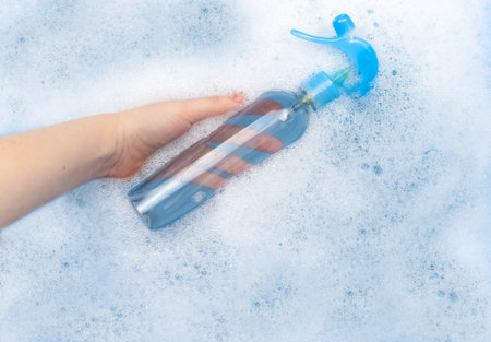 Bottles of detergents float in the foam. The concept of the dangers of household chemicals. Sodium...