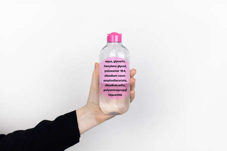 A woman is holding an micellar water. Harmful composition of ingredients. The concept of hazardous...
