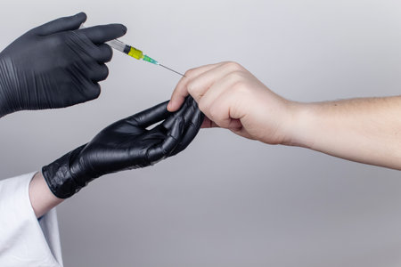 An orthopedic surgeon gives an injection in the finger joint. Treatment of osteoarthritis with hormonal drugs or drugs based on hyaluronic acid. Help with diseases that damage the cartilage of the jointの写真素材