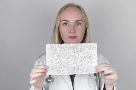 A neurologist examines an encephalogram of a patient's brain. Schedule of electroencephalograms - study of brain currents for signs of epilepsy and pathologies of the nervous systemの写真素材