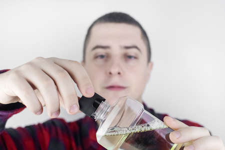 Close-up of a man in the bathroom using a mouthwash. Dental care concept. Procedure after brushing your teeth. Antibacterial mouth liquid. Pours, rinses and spits out liquid. Man look in the mirrorの写真素材