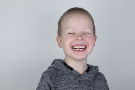 Close-up of a blond boy who smiles into the frame. White milk teeth. Perfect smile. The concept of...