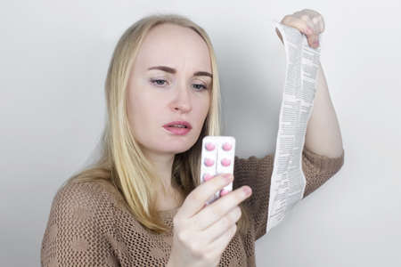 The girl on a white background reads the instructions for medicines. The woman looks at the list and...