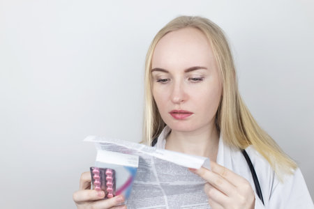 The doctor on a white background reads the instructions for medicines. The specialist looks at the...