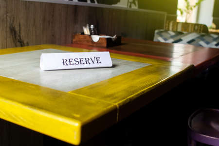 The flying around the plate is reserved, which stands on the wooden table in the restaurant....