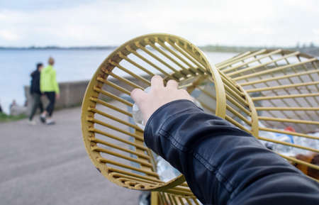 A man tosses a plastic bottle into a plastic container for collection. Recycling and disposal of plastic. The concept of maintaining cleanliness, order and care for the environment.の写真素材