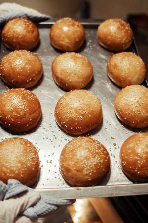 The baker takes out freshly baked rolls and bread from the oven. Homemade cakes close up. Home...