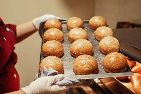 The baker takes out freshly baked rolls and bread from the oven. Homemade cakes close up. Home...