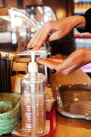A sanitizer is on the bar in a cafe. Hands should be cleaned before servicing. Quarantine due to virus 19. Service in a pandemic. Female hands use alcohol gel.の写真素材