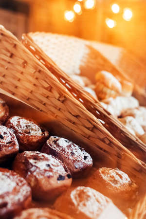 Close-up of muffins on a tray. Powdered sugar cakes. The work of the confectionery industry. Each cupcake is wrapped in paper wrapping. Vertical photoの写真素材