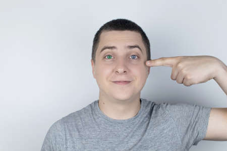 A man with different color eyes looks into the frame. The right eye is blue and the left is green. Heterochromia. Gene mutation. Multi-colored eyes.の写真素材