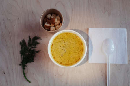 Close-up of mushroom soup in a paper glass. Takeaway food in the restaurant. The concept of vegetarian fast food in the meal industry. Pieces of crackers float in the broth.の写真素材