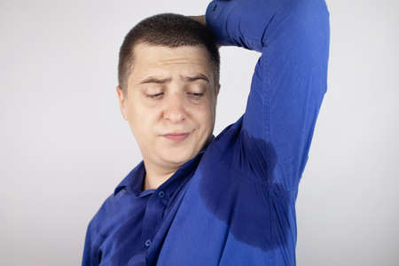 The man shows his sweaty armpits to the camera. Close-up of sweat drops. Gland problems. Hyperhidrosis, increased sweating, anhidrosis. Concept of treatment for violations of the mechanisms secretion.の写真素材