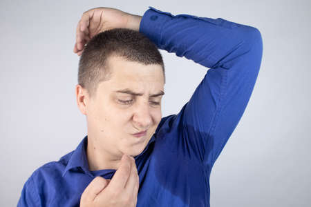 The man shows his sweaty armpits to the camera. Close-up of sweat drops. Gland problems....
