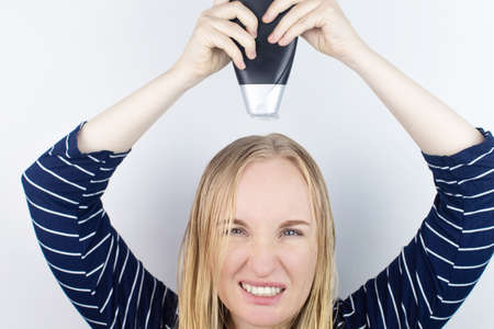 The girl looks in the mirror at her oily hair, then takes a shampoo to treat oily hair. Problematic...