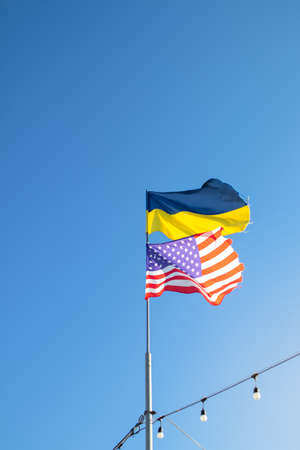 Ukrainian and American flag on a blue sky background. Friendship of peoples and diplomatic mission....
