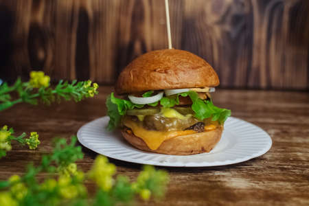 Close-up of a standard burger. Adult fast food in a restaurant or cafe. Macro photo of burger ingredients with meat, cheese and herbs. Eco burgers for the whole familyの写真素材