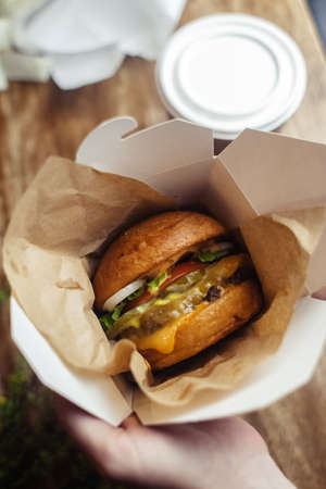 Close-up of a standard burger. Adult fast food in a restaurant or cafe. Macro photo of burger ingredients with meat, cheese and herbs. Eco burgers for the whole familyの写真素材