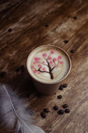 Drawings on coffee. Male and female cappuccino decoration. Hot drink in a paper cup. Picture of a chocolate mountain and Japanese cherry blossom. Food industry creativity conceptの写真素材