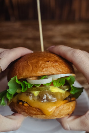 Close-up of a standard burger. Adult fast food in a restaurant or cafe. Macro photo of burger ingredients with meat, cheese and herbs. Eco burgers for the whole familyの写真素材