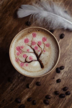 Drawings on coffee. Male and female cappuccino decoration. Hot drink in a paper cup. Picture of a chocolate mountain and Japanese cherry blossom. Food industry creativity conceptの写真素材