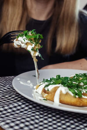 Pancakes with cheese on a plate in a restaurant. Breakfast at the cafe. A woman eats pancakes for breakfast from disposable dishes. Top view and vertical photoの写真素材
