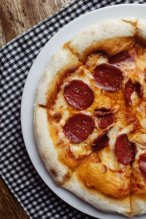 Pepperoni pizza close up. A dish covered with sausage rings and herbs. Italian cuisine in restaurants and cafes. The concept of meat ingredients in cooking.の写真素材