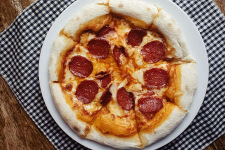 Pepperoni pizza close up. A dish covered with sausage rings and herbs. Italian cuisine in restaurants and cafes. The concept of meat ingredients in cooking.の写真素材