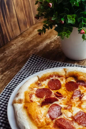 Pepperoni pizza close up. A dish covered with sausage rings and herbs. Italian cuisine in restaurants and cafes. The concept of meat ingredients in cooking.の写真素材