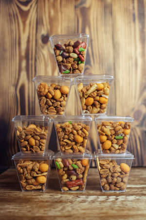 Close-up of a beer snack. Hazelnuts, cashews and peanuts with different flavors in transparent packaging. Snacks go with alcohol. Takeaway food. Conceptの写真素材